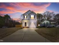 Charming two-story home with a well-manicured lawn and inviting curb appeal showcased by a colorful sunset at 717 Utley St, Holly Springs, NC 27540