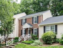Charming two-story brick home featuring black shutters, white railings, and lush landscaping at 7312 Sweet Bay Ln, Raleigh, NC 27615