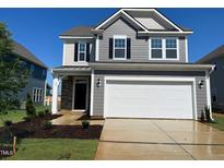 Two-story home featuring gray siding, stone accents, two-car garage, and well-manicured lawn at 88 Willow Cameron Way, Angier, NC 27501