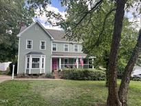 Charming two-story home features a pink door, bay window, covered front porch, and beautifully landscaped yard at 8808 Colesbury Dr, Raleigh, NC 27615