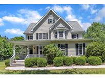 Charming two-story home featuring black shutters, a covered front porch and manicured landscaping at 1123 Poplar Forest Ln, Pittsboro, NC 27312