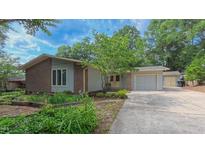 Charming exterior elevation features a brick facade, attached garage, and mature landscaping at 1815 Hawthorne Ln, Burlington, NC 27215