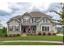 Charming two-story home featuring stone accents, gray siding, and a welcoming front porch with rocking chairs at 200 Baskerville Ct, Holly Springs, NC 27540