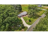 An aerial view of a single-story brick home with a long driveway and mature trees, complemented by a lush green lawn at 2291 Gentry Ridge Rd, Roxboro, NC 27574