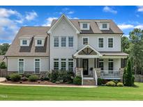 Beautiful two-story home featuring a manicured lawn and a charming covered front porch at 2300 Ginger Gold Court, Apex, NC 27539