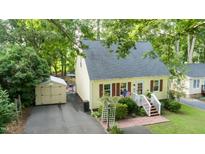 Charming home featuring yellow siding, brick stairs, an American flag, a shed, and a well-manicured yard at 2410 Wade Hampton Rd, Hillsborough, NC 27278