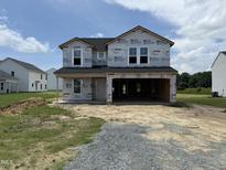 New two-story home with visible framing awaits completion with a two-car garage and landscaped yard at 29 Chloe Ct, Selma, NC 27576