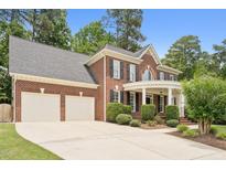 Traditional brick home with a two-car garage, manicured landscaping, and a welcoming front porch with white pillars at 325 Wescott Ridge Dr, Holly Springs, NC 27540