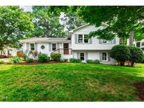 Charming two-story home with white painted brick, gray shutters, mature trees, and a beautifully landscaped front yard at 433 Rosehaven Dr, Raleigh, NC 27609