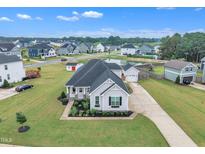 Inviting single-Gathering home boasts lush landscaping, a charming front porch, and an extended driveway in a desirable community at 450 S Parliament Way, Clayton, NC 27520