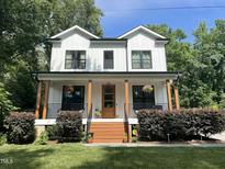 Charming two-story white farmhouse with inviting front porch, beautiful landscaping, and updated windows at 517 Bart St, Raleigh, NC 27610