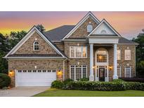 Elegant brick home showcasing a manicured lawn, a two-car garage, and grand entrance with stately white columns at 825 Highwater Pl, Fuquay Varina, NC 27526