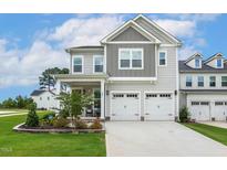 Charming two-story home with a two-car garage, covered porch, and landscaped front yard at 100 Emory Bluffs Dr, Holly Springs, NC 27540