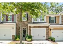 Charming townhome featuring a stone facade, a one-car garage, and meticulously landscaped front yard at 1213 Silver Beach Way, Raleigh, NC 27606