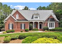 Charming brick home with a manicured lawn, lush landscaping, and covered front porch at 122 Barringer Dr, Garner, NC 27529