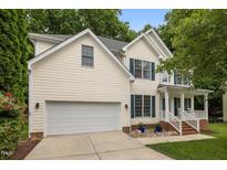 Charming two-story home with a two-car garage, blue shutters, front porch, and landscaped yard at 15 Smoketree Ct, Durham, NC 27712