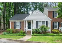 Charming Cape Cod-style home featuring a brick and siding facade, complemented by lush greenery and a welcoming front porch at 213 Bracken Ct, Raleigh, NC 27615
