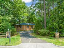 Charming brick home nestled among mature trees, featuring a long driveway and well-maintained landscaping at 3006 Pump Station Ln, Durham, NC 27712