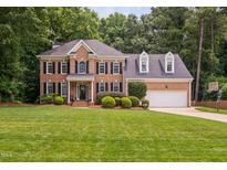Beautiful two-story brick home with a well-manicured lawn and mature landscaping at 317 Chanticlair Dr, Apex, NC 27502