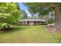 Charming brick home with a welcoming yellow front door and large, mature trees in a well-manicured lawn at 658 Hiawatha Pl, Burlington, NC 27217