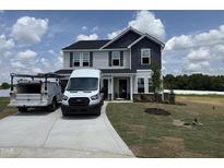 Two-story home with gray siding, dark blue gables, manicured lawn and long driveway at 88 W Emily Gardens Dr, Selma, NC 27576