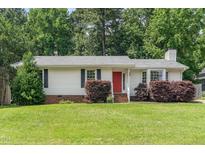 Charming single-story home with a well-maintained lawn, red front door and manicured shrubbery at 9709 Batesville Dr, Raleigh, NC 27617
