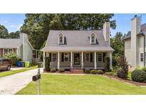 Charming home featuring a beautifully landscaped front yard, dormer windows and inviting porch with black shutters at 1033 Mills St, Raleigh, NC 27608