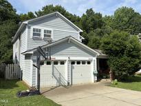 Traditional two-story home featuring a two-car garage, light blue siding, well-maintained yard, and mature trees for added privacy at 10415 Neland, Raleigh, NC 27614