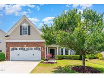 Charming home with a brick and vinyl exterior, two-car garage, mature trees, and well-maintained landscaping at 1108 Forest Willow Ln, Morrisville, NC 27560