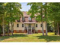 Charming two-story home with a brick foundation, light yellow siding, and mature trees at 1909 Ira Rd, Efland, NC 27243