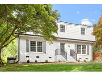 Charming two-story home with a freshly painted white brick exterior, manicured lawn, and attractive landscaping at 3129 Merrianne Dr, Raleigh, NC 27607