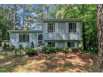 Charming split-level home featuring light blue siding, white shutters and a beautifully landscaped front yard at 320 Bainbridge Cir, Garner, NC 27529