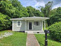Charming single-story home features a welcoming front porch, complemented by a lush green lawn and mature trees at 511 Commonwealth St, Durham, NC 27703