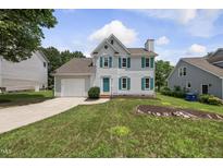 Charming two-story home features a landscaped yard, attached garage, and cheerful turquoise shutters at 5317 Peacenest Dr, Raleigh, NC 27610