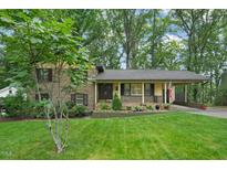 Charming brick home with a well-manicured lawn, mature trees, and inviting curb appeal at 5523 Newberry Dr, Raleigh, NC 27609