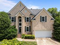 Charming two-story brick home featuring a well-manicured lawn, attached garage, and decorative shutters at 105 Mcnaughton Ct, Garner, NC 27529