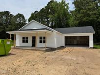 New construction featuring white siding, gray shingles, an attached two-car garage, and a charming front porch at 107 Lynn Ln, Selma, NC 27576