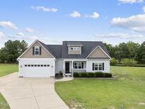 Inviting exterior showcases well-manicured lawn, attached two-car garage, and charming front porch at 241 Fox Run, Benson, NC 27504
