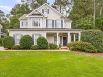 Charming two-story home featuring a lush green lawn, covered front porch, and classic architectural details at 244 Elmcrest Dr, Holly Springs, NC 27540