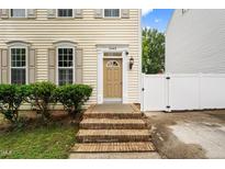 Inviting entrance with brick steps, tan door, and stylish shutters at this charming home at 2445 Sapphire Valley Dr, Raleigh, NC 27604