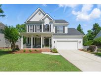 Charming two-story home with a well-manicured lawn, inviting porch swing, and attached two-car garage at 2933 Creek Moss Ave, Wake Forest, NC 27587
