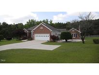 Charming brick home features a well-manicured lawn and attached two-car garage at 3409 Bennyfield Ct, Fuquay Varina, NC 27526
