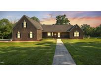 Beautiful brick home featuring a well-manicured lawn, a cozy front porch, and a walkway to the entrance at 3537 Sweetgum Rd, Gibsonville, NC 27249