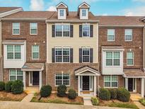 Charming brick townhome featuring black shutters, dormer windows, and a welcoming covered entryway at 6027 Kentworth Drive. Dr, Holly Springs, NC 27540