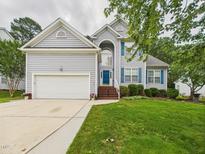 Charming two-story home featuring a well-manicured lawn, two-car garage, and a welcoming blue front door at 7501 Montibillo Pkwy, Durham, NC 27713