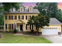 Charming yellow two-story home with black shutters and manicured lawn and white garage door at 1001 Kingsway Dr, Apex, NC 27502