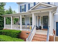 Inviting front porch with white columns, black railings, and a brick base, perfect for relaxing outdoors at 101 Ironcreek Pl, Apex, NC 27539
