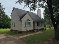 Traditional home with a chimney, vinyl siding, and a well-maintained lawn, offering comfort and charm at 101 New Castle Ct, Youngsville, NC 27596