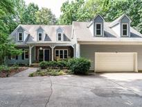 Charming traditional home featuring a two-car garage and dormer windows, nestled among lush trees at 10101 Daviton Ct, Raleigh, NC 27615