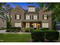Charming two-story brick home with a beautifully landscaped front yard and a welcoming front porch at 109 Aspenridge Dr, Holly Springs, NC 27540